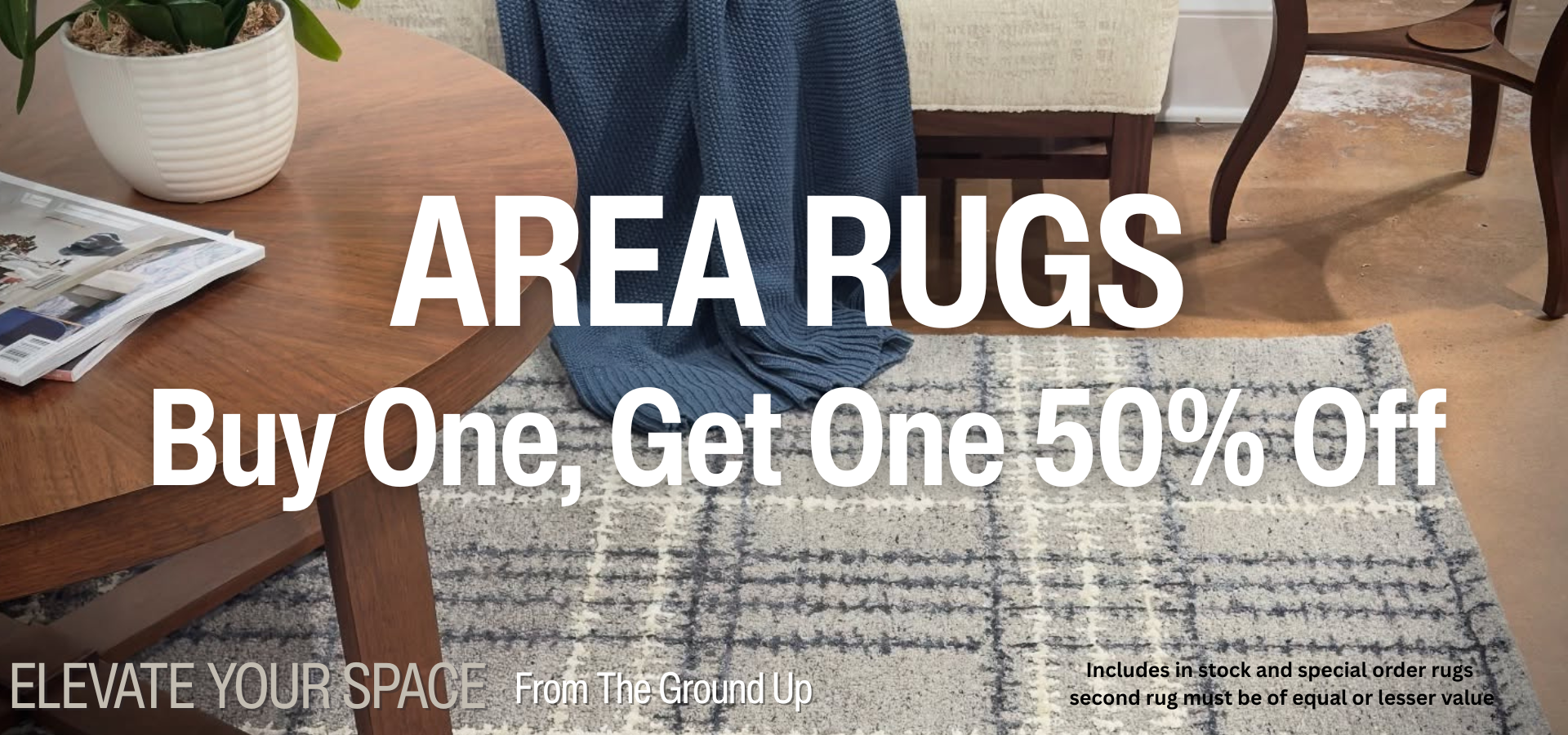 An area rug sale banner showing a cozy, decorated space with a gray plaid rug. The image has large white text that says "AREA RUGS" and "Buy One, Get One 50% Off". Small text in the corner notes the sale includes in-stock and special order rugs, and the second rug must be of equal or lesser value.